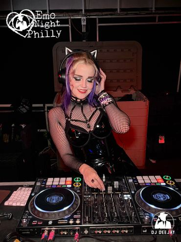 DJ in cat ears and fishnet top mixing music at Emo Night Philly event.