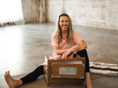 Woman sitting cross-legged on the floor with a box in an empty room.