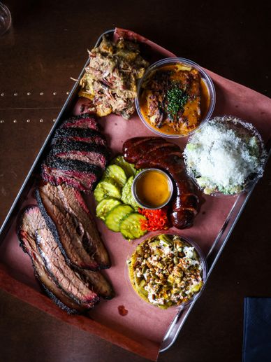 Tray of barbecue with brisket, sausage, pickles, and sides.