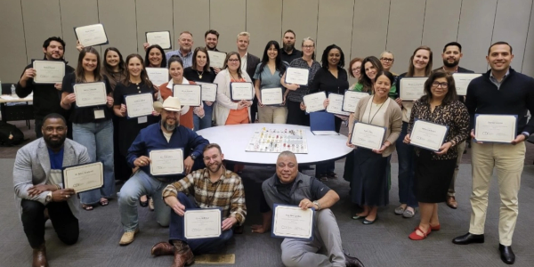 Group holding certificates in a celebratory setting.