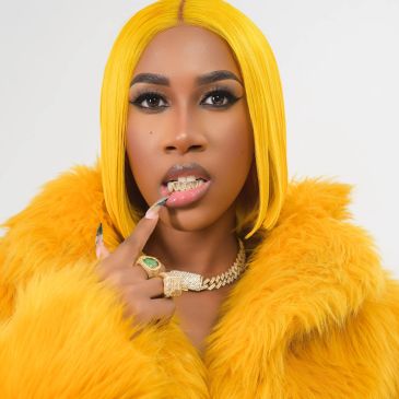 Person in vibrant yellow fur coat and matching hair with gold grillz.