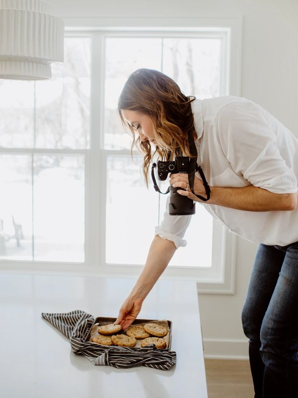 Woman taking photos of cookies in a bright kitchen.