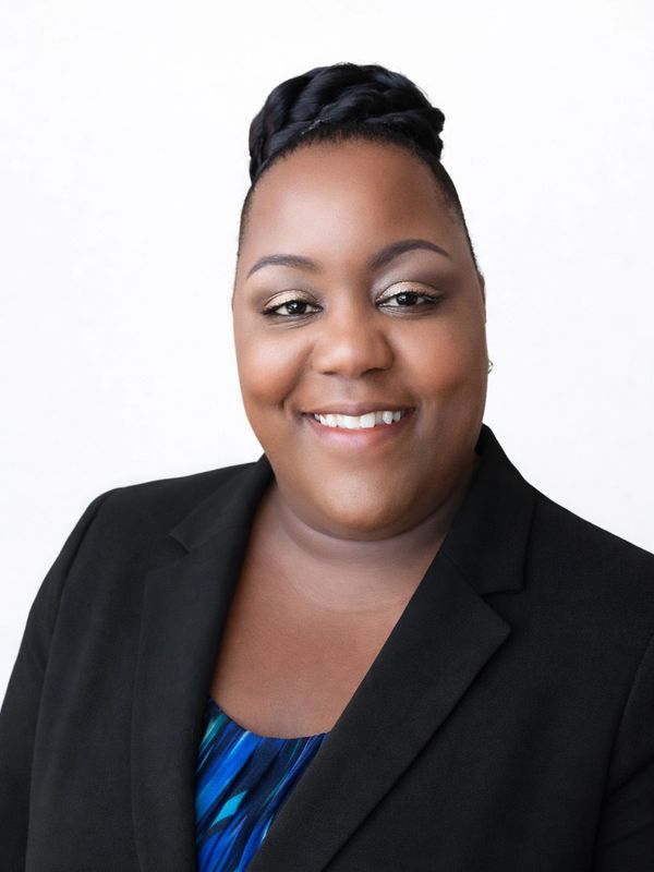 Professional woman smiling, wearing a black blazer and blue top.