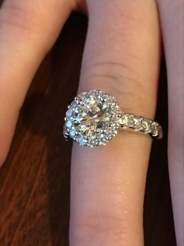 Sparkling diamond engagement ring on finger with halo setting.