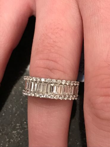 Elegant diamond ring with baguette and round stones on a finger.
