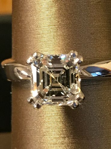 Close-up of a square-cut diamond ring with a silver band.