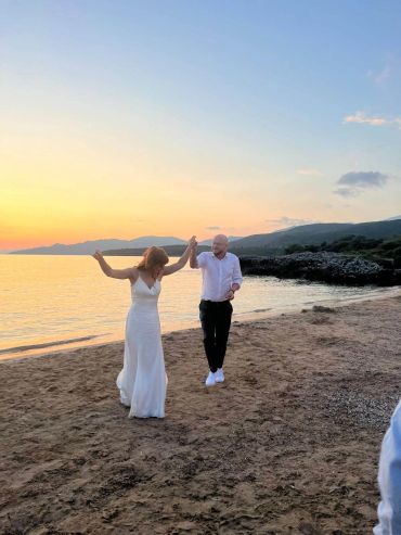 Couple dancing joyfully on the beach at sunset.