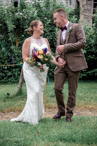 Bride and groom smiling at each other outdoors on their wedding day.