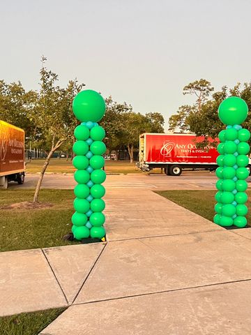 Tall columns of green balloons at a park entrance.