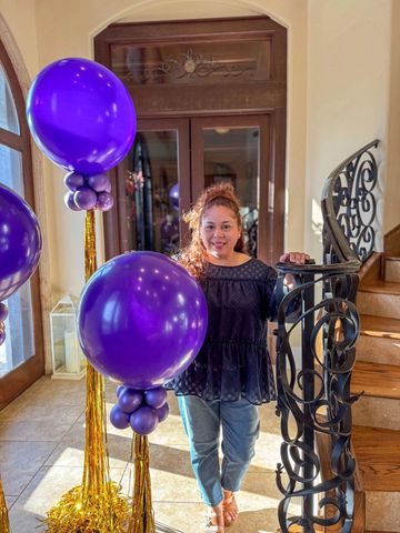 Young woman standing beside purple balloon decorations indoors.