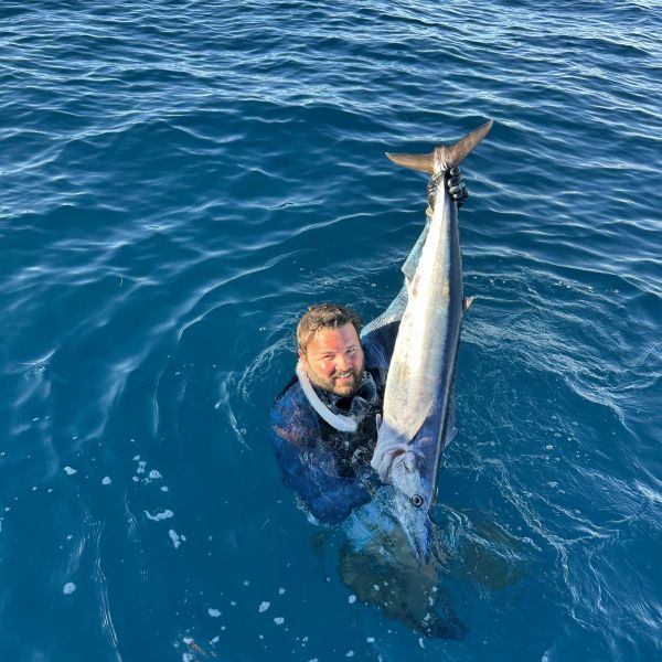 Man holds large fish in the ocean.