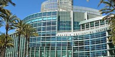 Exterior view of Anaheim Convention Center with palm trees against blue sky.