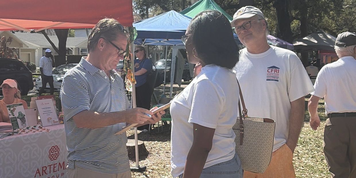 People interacting at an outdoor community event with informational booths and tents.