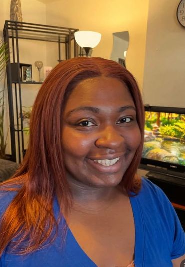 Smiling woman with reddish hair and blue top indoors.
