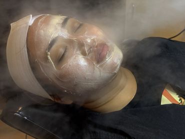 Person with a facial mask relaxing during a skincare steam treatment.