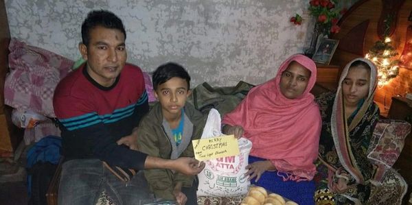Family sitting together holding a Christmas gift bag indoors.