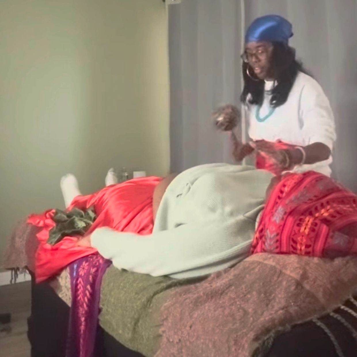 Person performing a spiritual healing ritual on a person lying on a bed.
