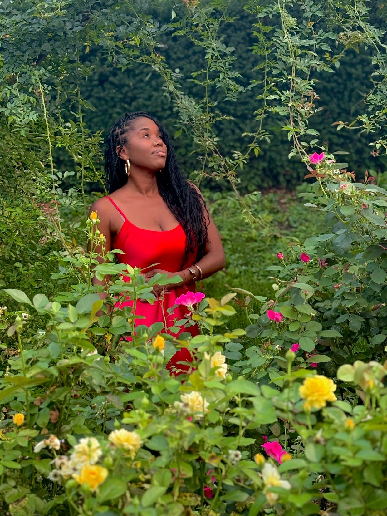 Woman in a red dress surrounded by flowers in a garden.