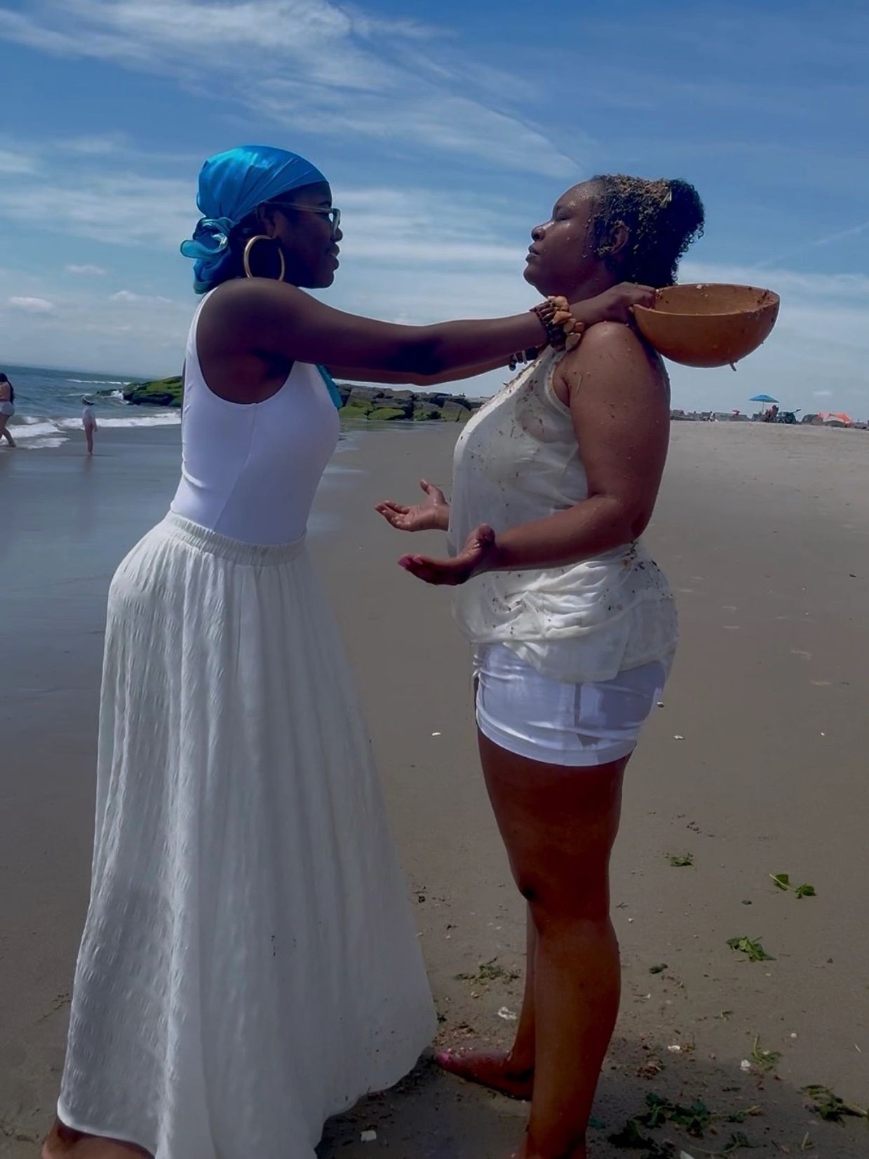 Two women performing a ritual on the beach.