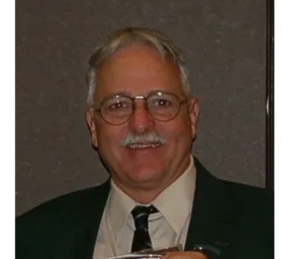 Smiling elderly man in glasses and suit.