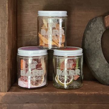 Three jars filled with dried fruit slices on a wooden shelf.