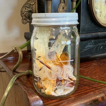 A glass jar filled with dried flowers on a wooden surface.