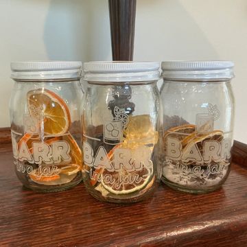 Three glass jars with dried citrus slices on wood.