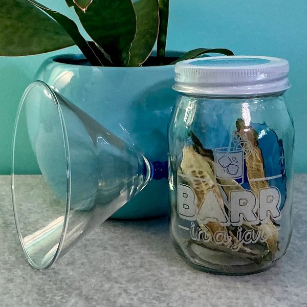 Glass jar with dried mushrooms next to a funnel and a blue plant pot.