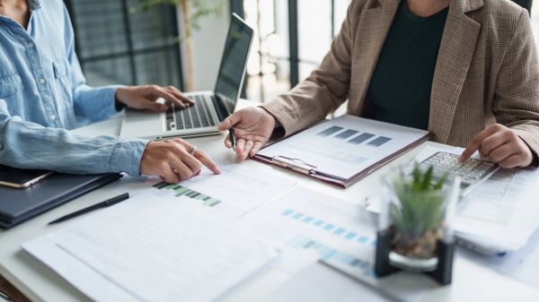 Two professionals analyzing financial charts and data in an office meeting.