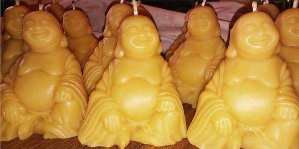 Beeswax Buddha candles arranged on a wooden surface.
