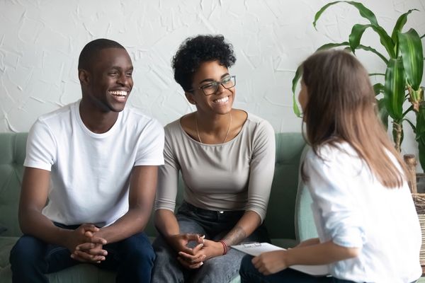 The couple appears to be smiling and engaged in the conversation with the counselor.