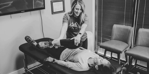 A therapist helps a patient stretch on a treatment table.