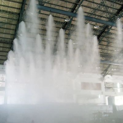 Indoor water fountain spraying high jets of water beneath a large industrial ceiling.