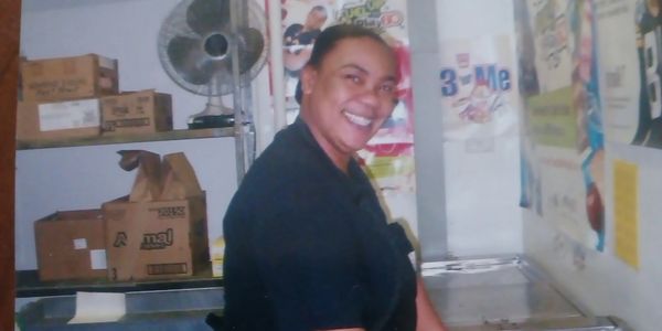 A smiling woman standing in a room with boxes and posters.