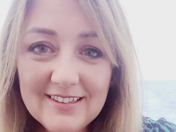 Close-up of a smiling woman with blonde hair and blue eyes.