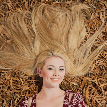 Woman lying on wood chips with spread blonde hair.