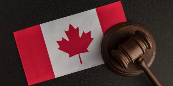Canadian flag next to a wooden judge's gavel.