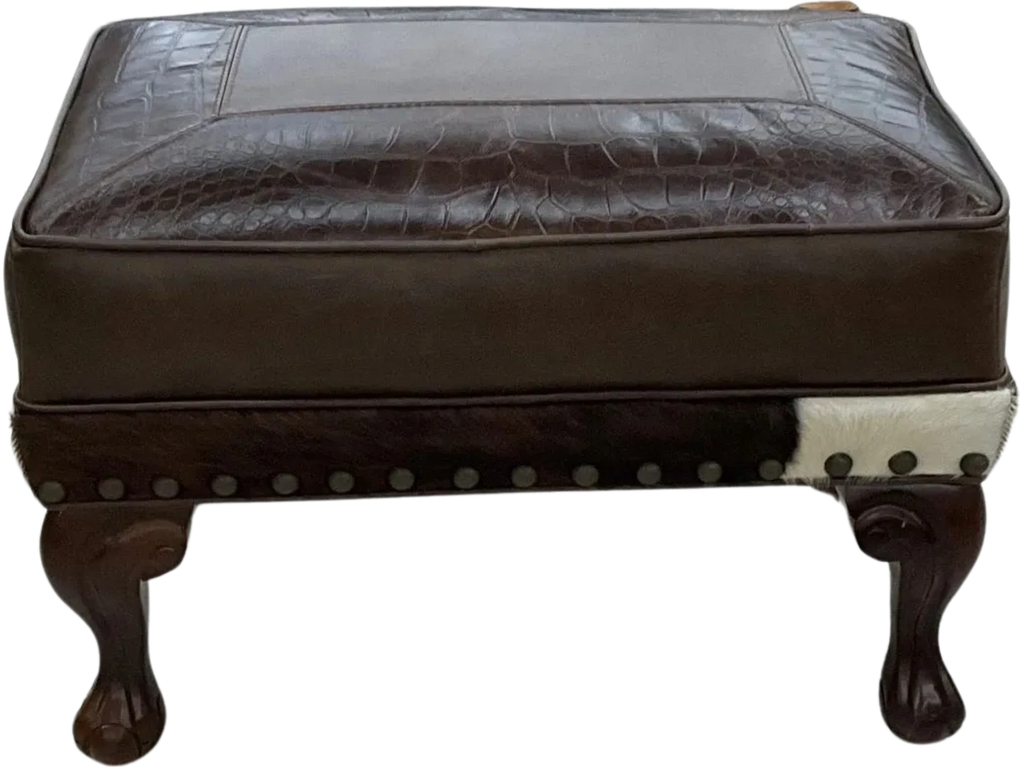 Elegant brown leather ottoman with carved wooden legs and nailhead trim.