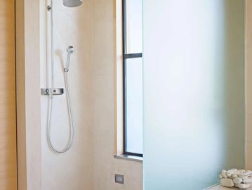 Minimalist shower area with a handheld showerhead and frosted glass partition.