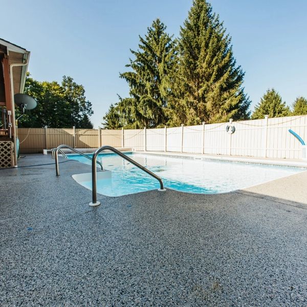 Decorative textured deck coating being applied around a pool in Edgewater, Florida.