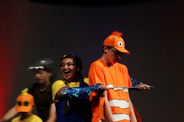 Kids in colorful costumes perform on stage.