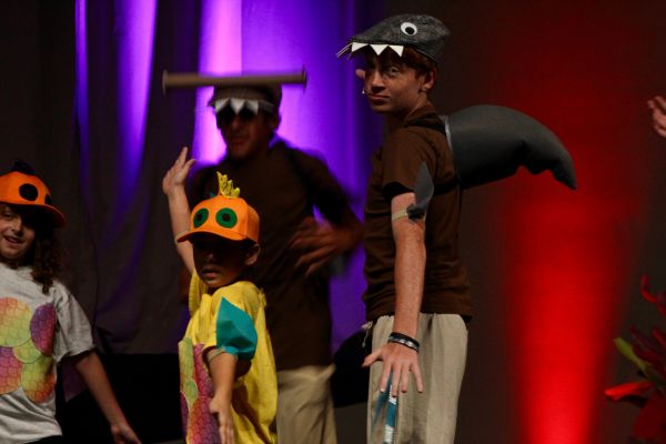 Kids in colorful costumes performing on stage.