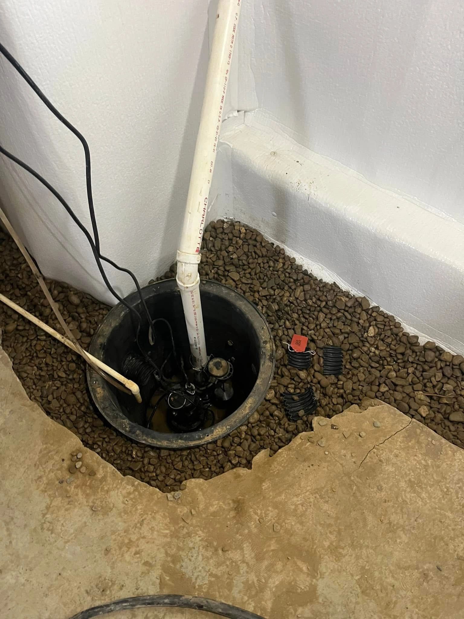 Basement sump pump pit with gravel and piping setup.basement waterproofing columbus