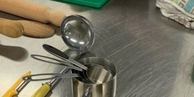 Kitchen utensils in a metal container on a stainless steel counter.