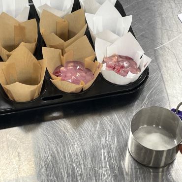 Muffin batter scooped into paper liners on a tray.