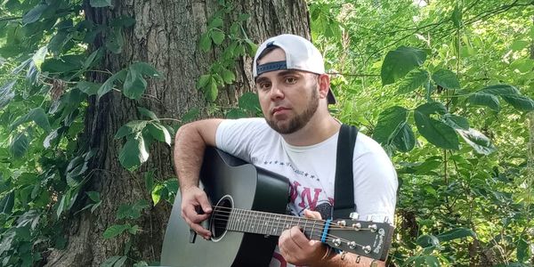 Man playing acoustic guitar outdoors.