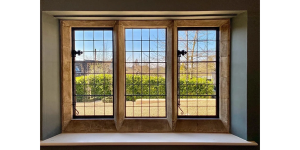 A three-paneled window with a garden view and blue sky.