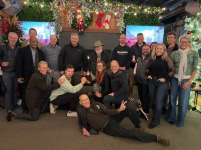 Group of people posing cheerfully indoors with holiday decorations.