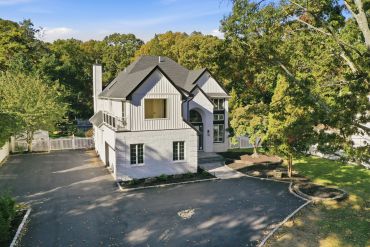 Large white house with black roof and spacious driveway.