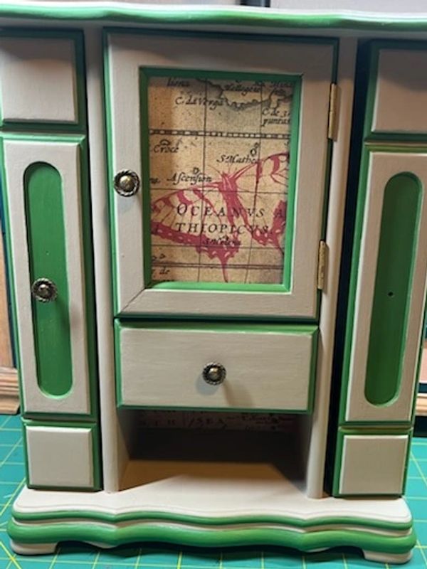 Small vintage wooden cabinet with green trim and a map design on the door.